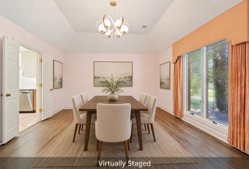 Dining area featuring a contemporary chandelier, vaulted ceiling, wood-finish flooring, and bright windows with exterior views