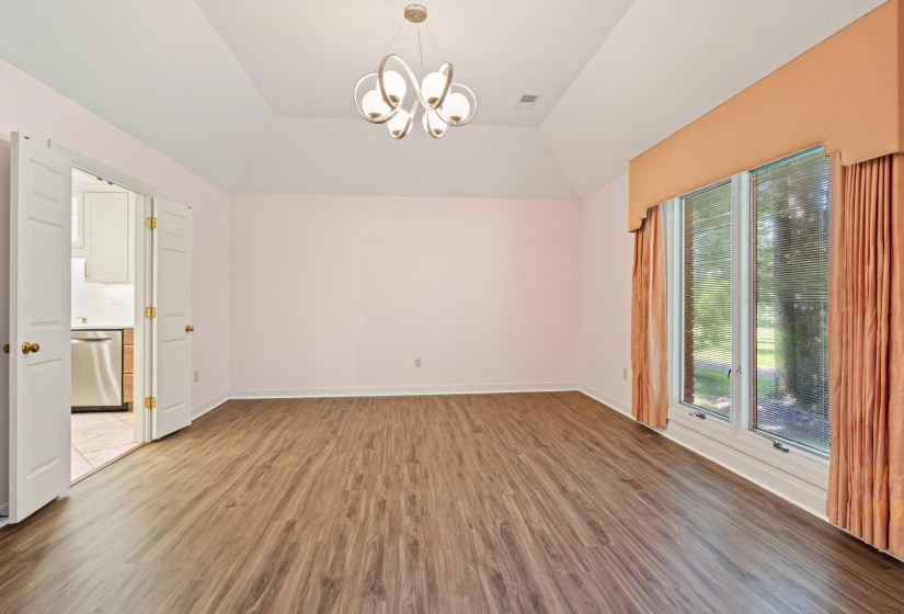 Spacious room featuring wood-finish flooring, a tray ceiling, and a contemporary chandelier