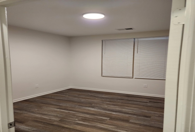 Room featuring wood-finish flooring, crisp white walls, and a recessed ceiling light