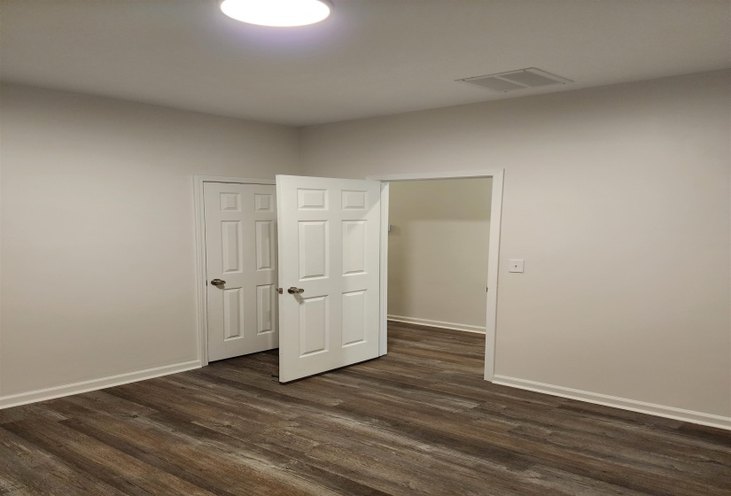 Room featuring wood-finish flooring, white baseboards, and neutral wall paint