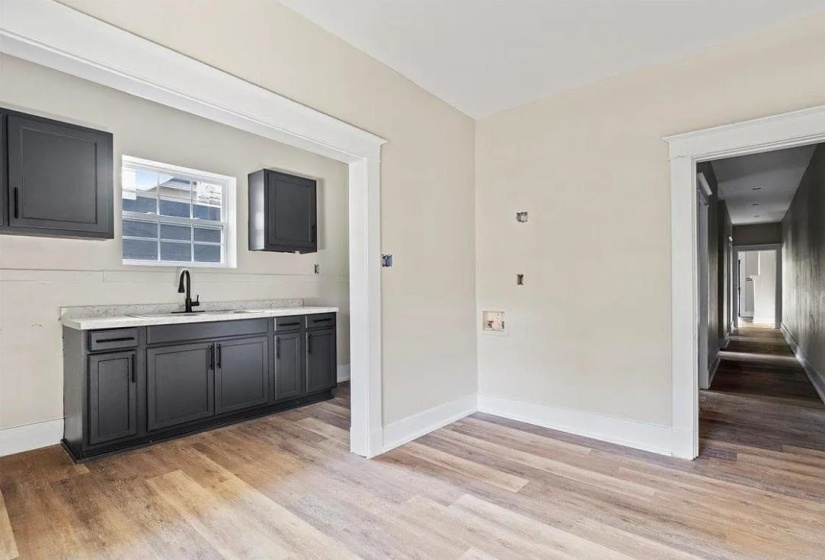 Dedicated laundry area featuring a utility sink with a matte black faucet, dark cabinetry, and a light-toned countertop