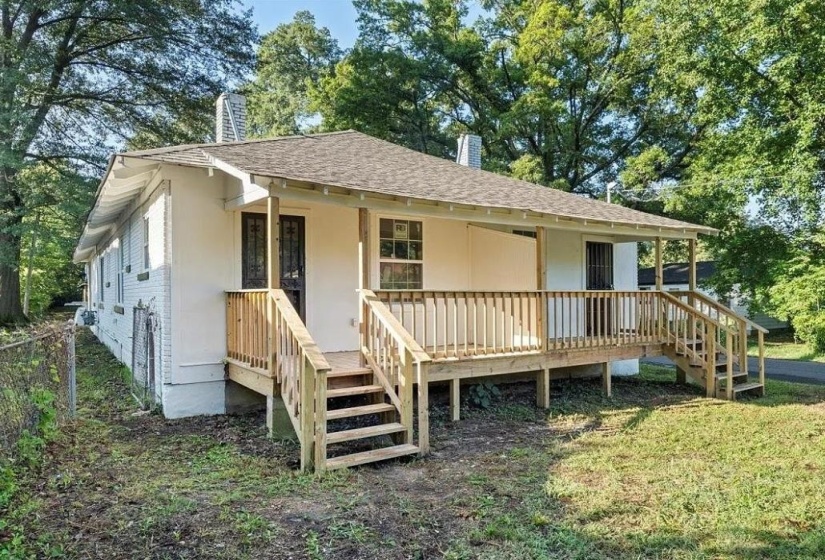 Rear exterior featuring a spacious wood deck, multiple stair access points, and a covered porch area