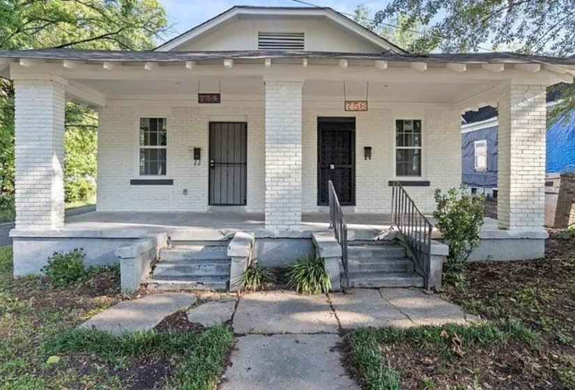Brick duplex with covered front porch, concrete steps, and iron railings