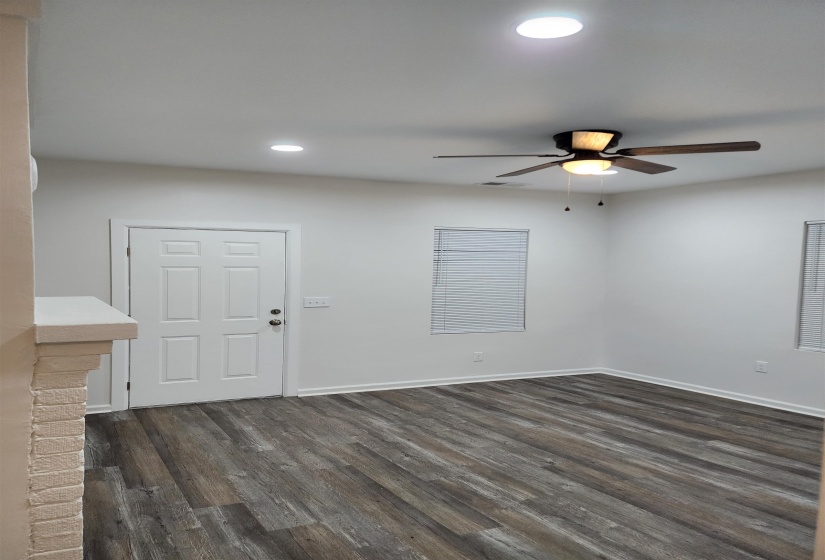 Spacious room featuring wood-finish flooring, white walls, and a ceiling fan with integrated lighting