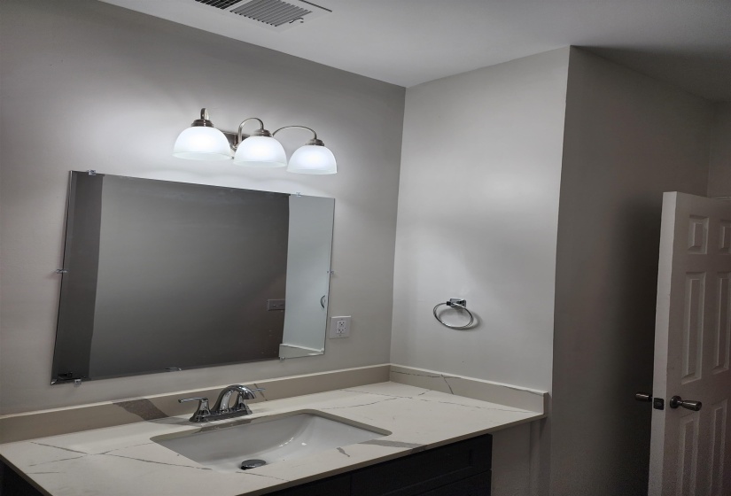 Bathroom vanity featuring a rectangular undermount sink, a chrome-finish faucet, and a light-toned countertop with veining