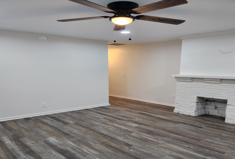 Interior space featuring wood-finish flooring, a white brick fireplace, a ceiling fan with integrated lighting, and recessed lighting