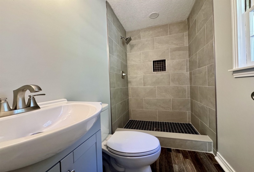 Bathroom featuring dark wood-style floors, vanity, a shower stall, and a textured ceiling