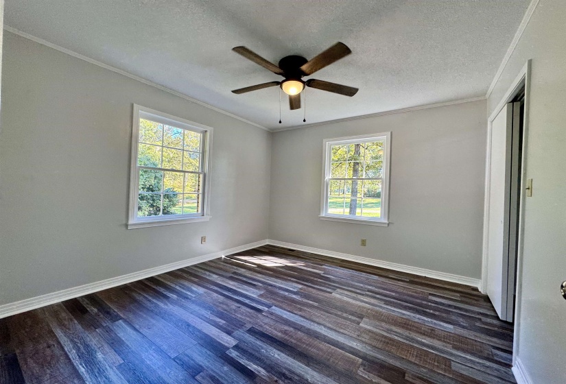 Unfurnished bedroom with crown molding, a textured ceiling, dark wood finished floors, and a ceiling fan