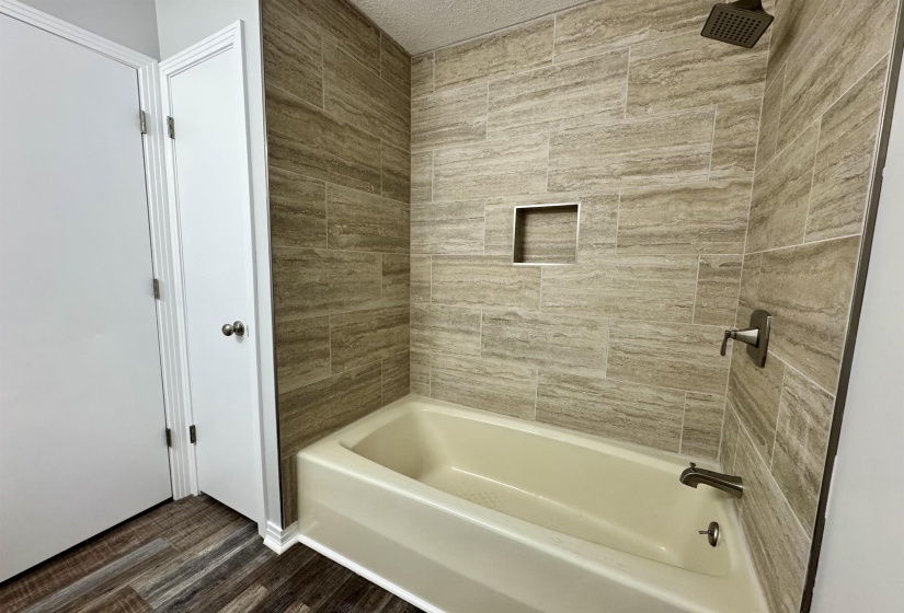 Bathroom with  shower combination and dark wood-type flooring