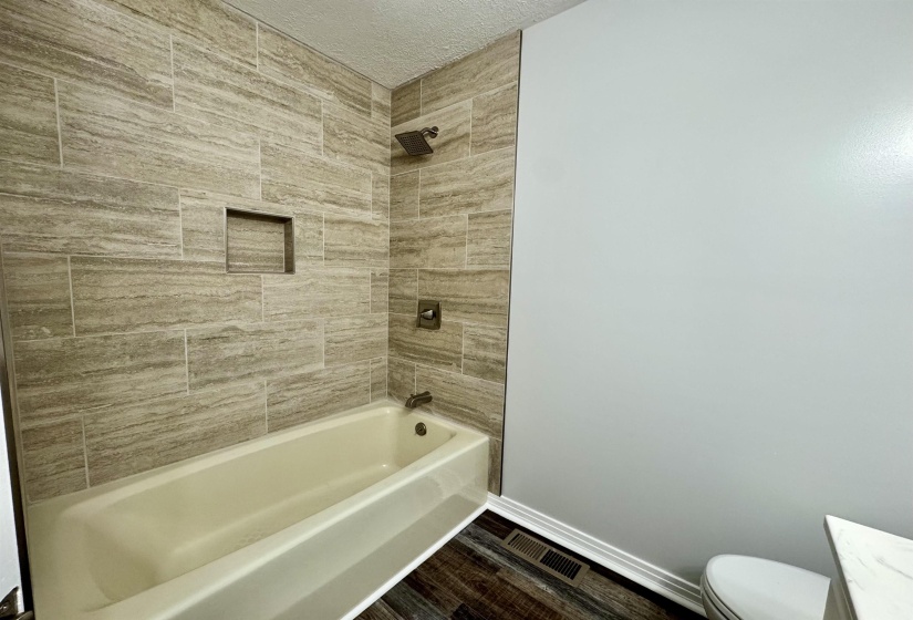 Bathroom with shower / tub combination, dark wood-style flooring, a textured ceiling, and vanity