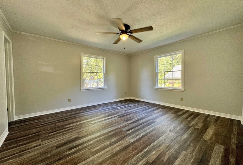 Unfurnished room with ornamental molding, dark wood finished floors, a textured ceiling, plenty of natural light, and a ceiling fan