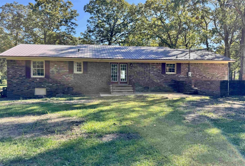 Rear view of property with brick siding, a metal roof, crawl space, and entry steps