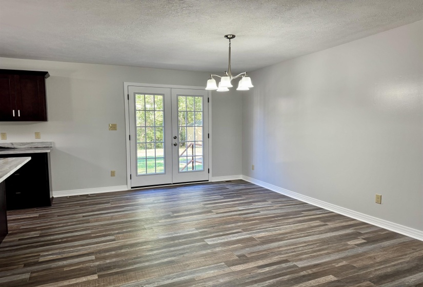 Unfurnished dining area with a chandelier, french doors, dark wood-style flooring, and a textured ceiling