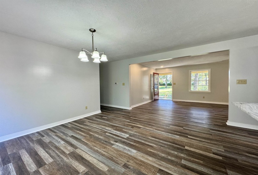 Empty room with dark wood-style flooring, a textured ceiling, and a chandelier
