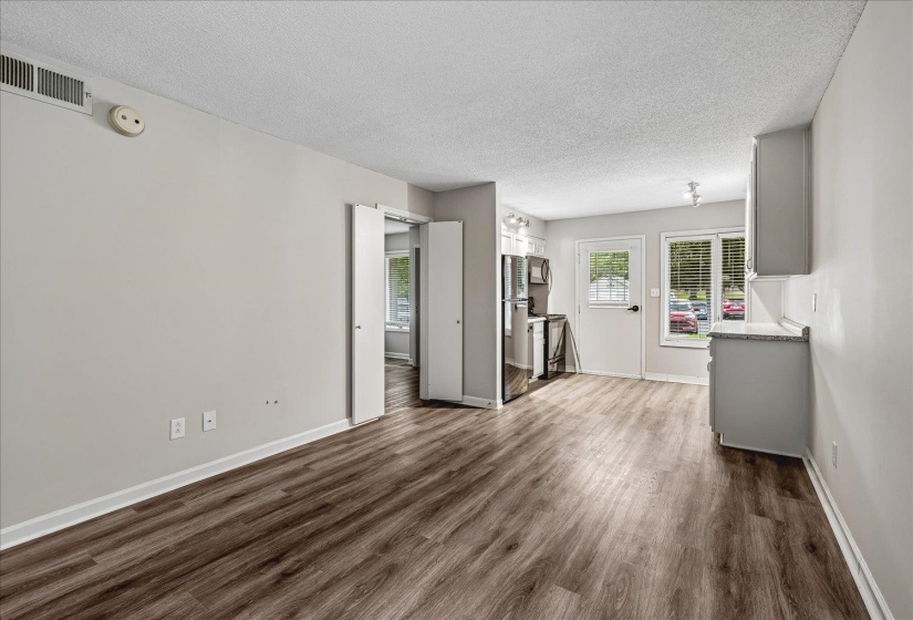 Open-concept living area featuring wood-finish flooring, a neutral color palette, and a kitchen area with light gray cabinetry
