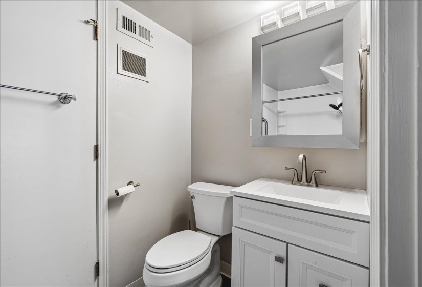Bathroom featuring a white vanity with integrated sink, brushed nickel faucet, and a wall-mounted medicine cabinet with overhead lighting