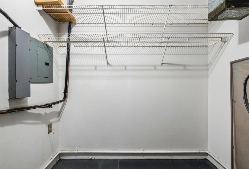 Utility space featuring a neutral wall finish, wall-mounted shelving, and an electrical service panel