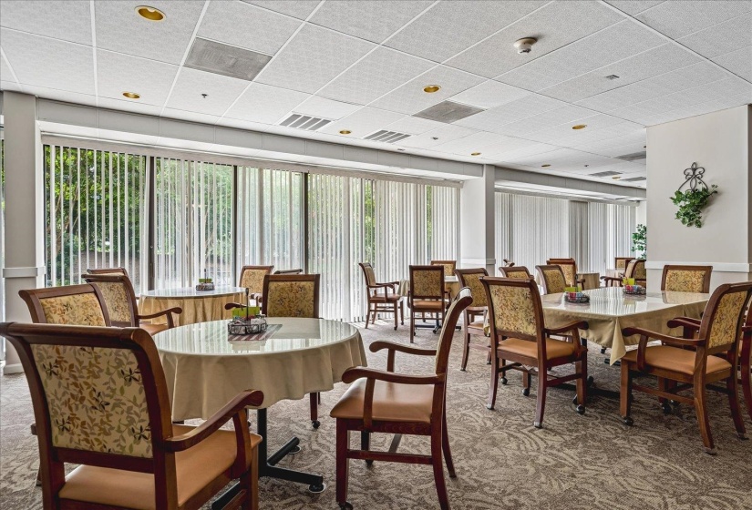 Spacious dining area featuring extensive window walls with vertical blinds, recessed lighting, and patterned carpeting