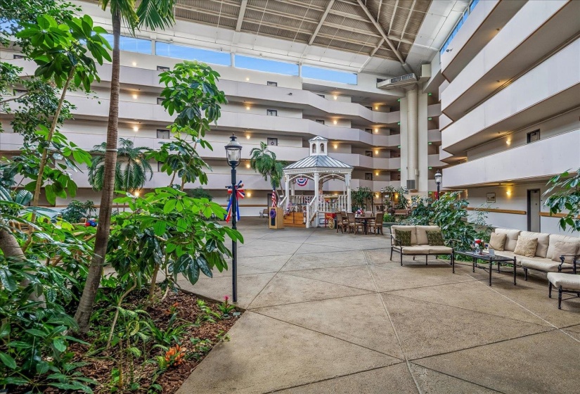 Spacious interior atrium featuring multiple levels of balconies, a central gazebo, and concrete flooring