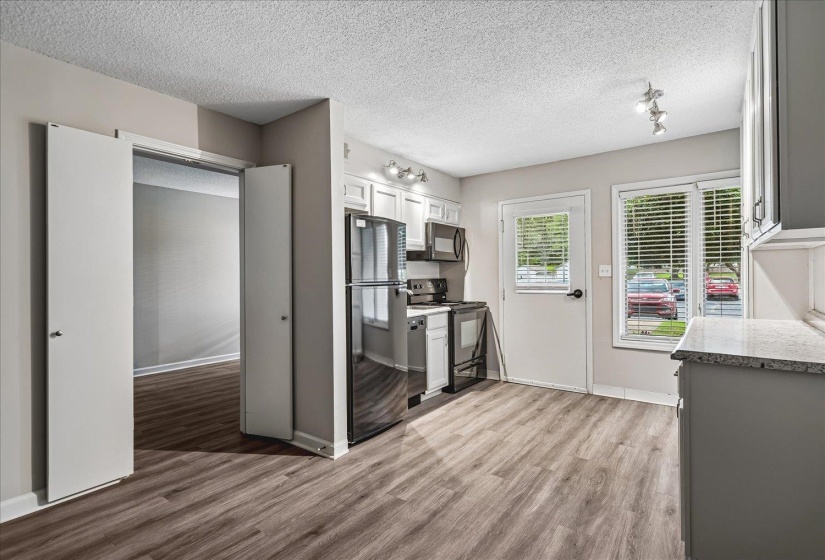 Kitchen featuring wood-finish flooring, white cabinetry, stainless steel appliances, and granite countertops