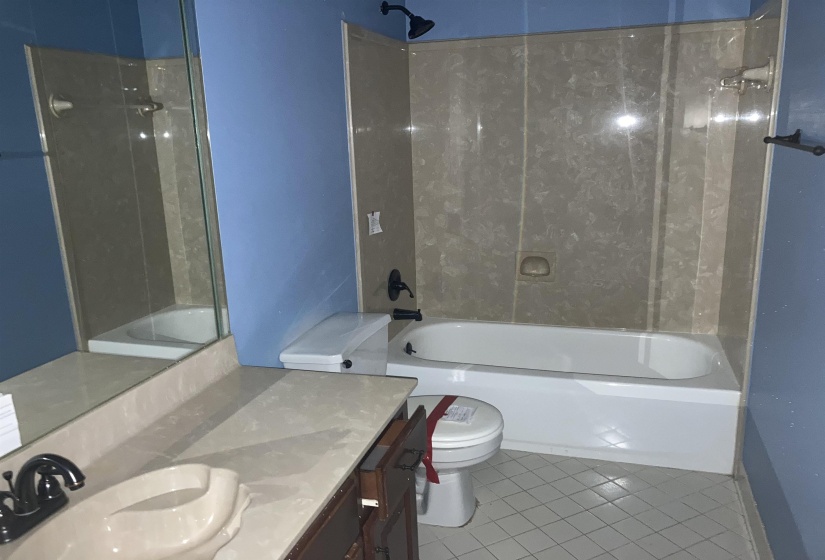 Bathroom featuring a full-sized bathtub with a surrounding panel enclosure and a dark bronze showerhead
