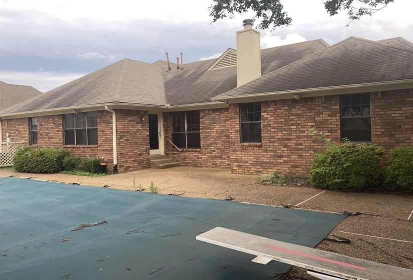 Brick exterior with multiple windows and a covered pool area