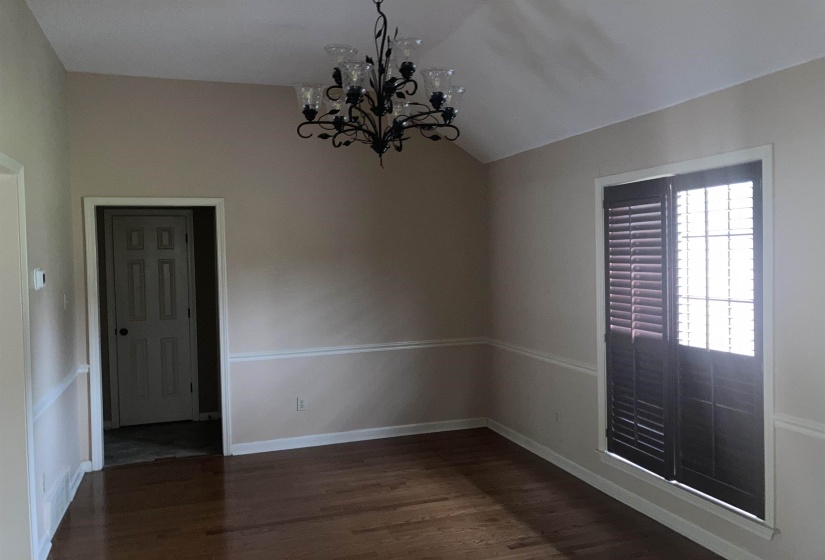 Spacious interior room featuring a vaulted ceiling and wood-finish flooring