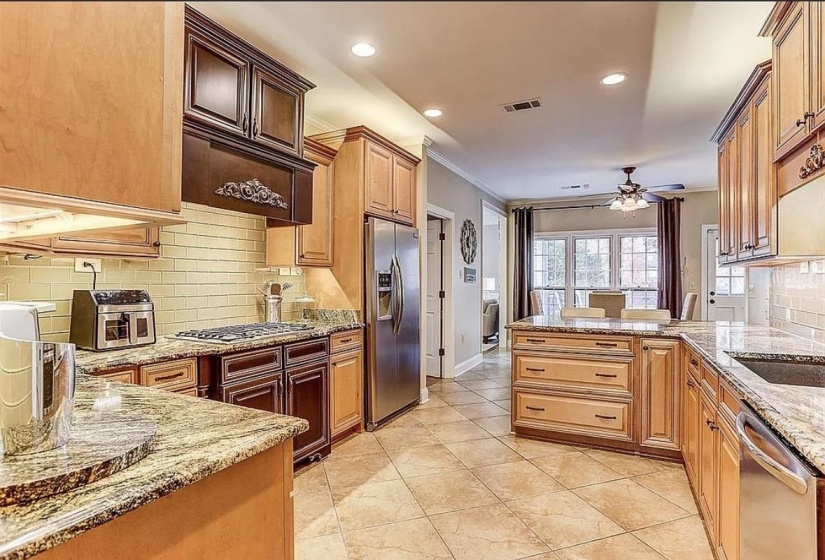 Spacious kitchen featuring light wood cabinetry, granite countertops, and a subway tile backsplash