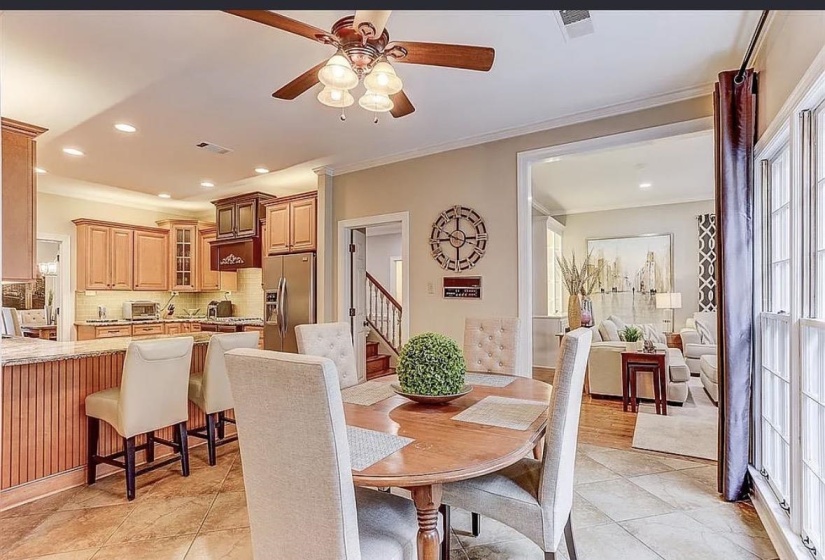 Spacious kitchen and dining area featuring tile flooring, a breakfast bar with seating, light wood cabinetry, stainless steel appliances, and recessed lighting