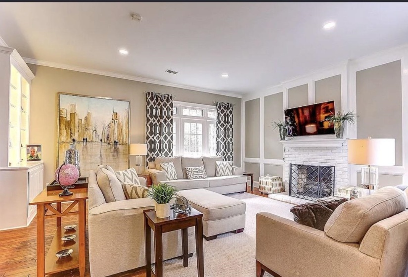 Spacious living area featuring a white brick fireplace with a mantel, recessed lighting, and crown molding