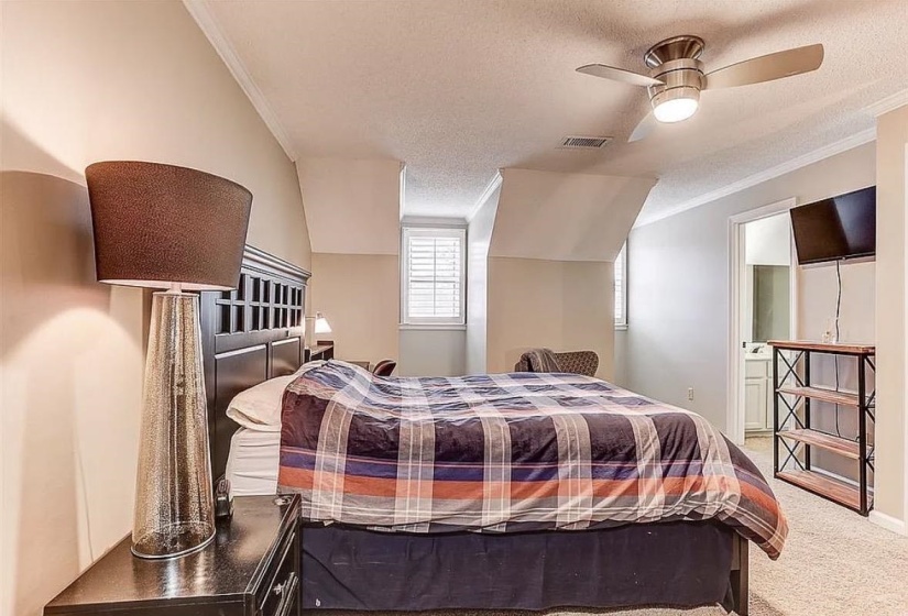 Bedroom with carpet flooring, a dark wood headboard, and a ceiling fan with integrated lighting