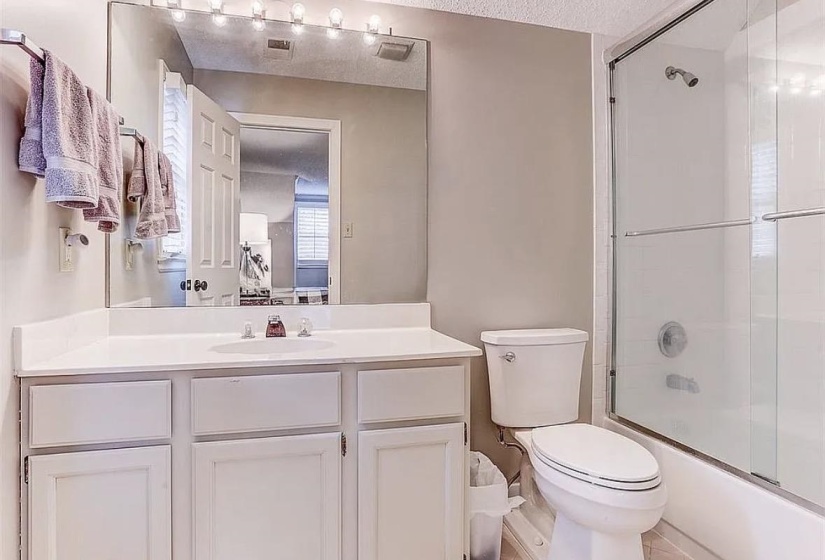Bathroom featuring a single vanity with white cabinetry, a built-in sink, and a large wall-mounted mirror