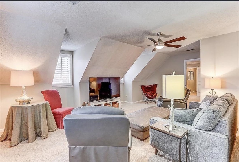 Carpeted bonus room with a sloped ceiling, recessed media nook, and a ceiling fan with integrated lighting
