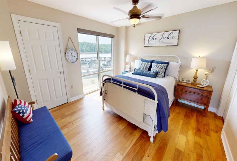 Bedroom featuring wood-finish flooring, a ceiling fan with integrated lighting, and a window with a water view