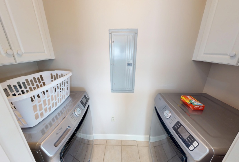 Dedicated laundry area featuring tile flooring, upper cabinetry, and a neutral wall color