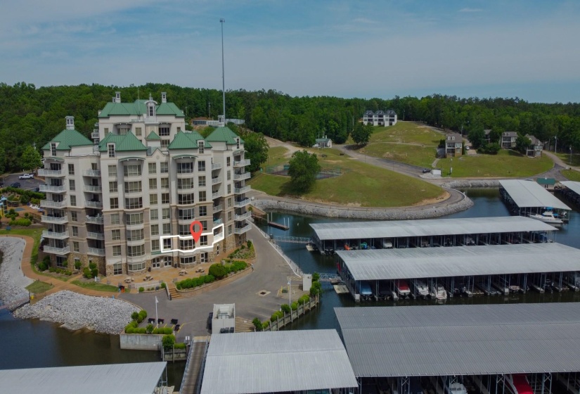 Waterfront condominium building with multiple balconies, green sloped roofs, and an expansive marina