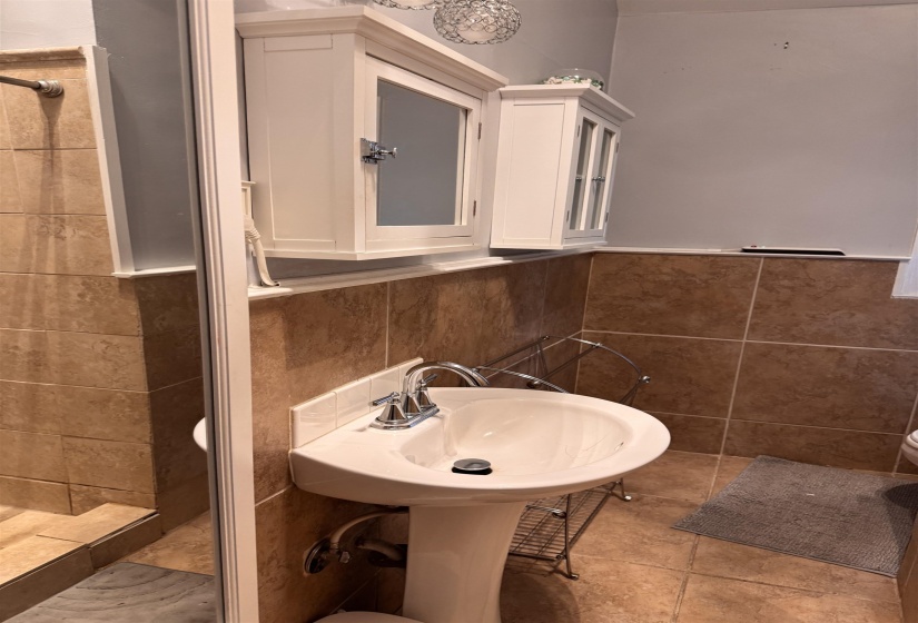 Pedestal sink with chrome fixtures and tiled flooring
