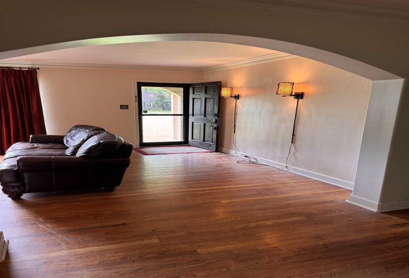 Hardwood flooring extends throughout this space, framed by an arched entryway
