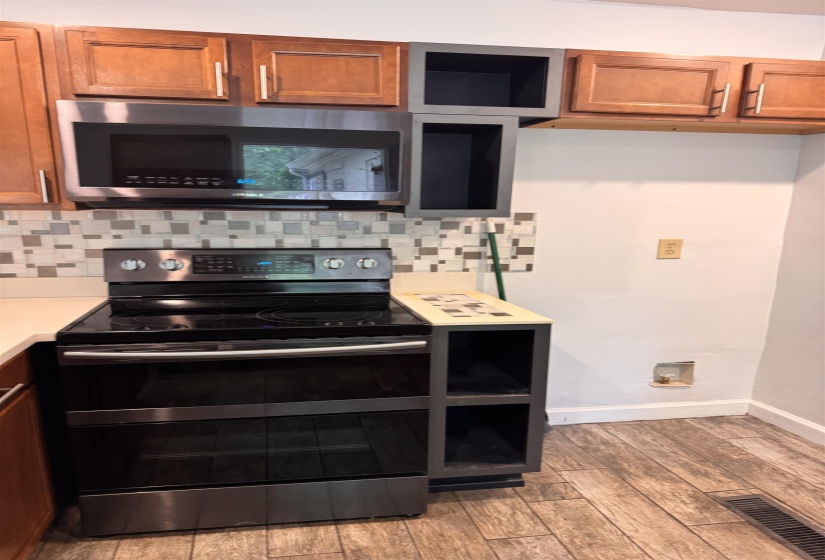Stainless steel range and built-in microwave complemented by wood cabinetry