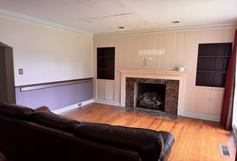 Hardwood flooring throughout featuring a fireplace with a stone surround and wood mantel