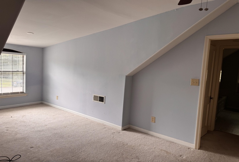 Carpeted room featuring a window with blinds, light blue walls, and white trim