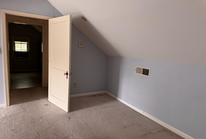 Carpeted room featuring a sloped ceiling, light blue and white painted walls, and a white interior door