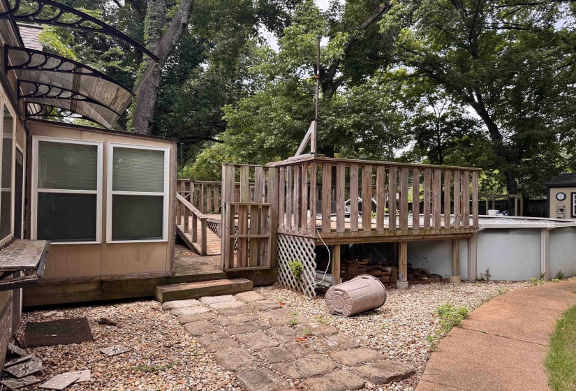 Multi-level wood decking with a built-in pool, gravel ground cover, and a concrete paver path