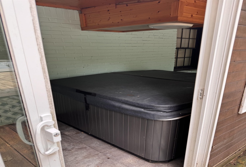 Covered patio area featuring a built-in spa, painted brick wall, wood plank ceiling, and recessed lighting