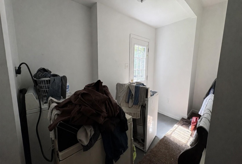 Laundry space with white painted walls, a light gray floor, and a white door with multiple glass panes