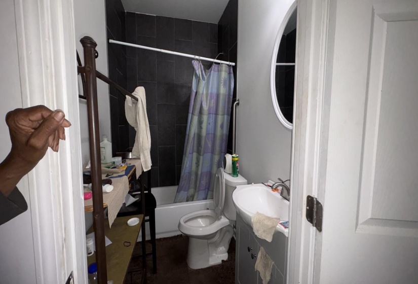 Bathroom featuring a white tub, dark wall tiling, and a white toilet