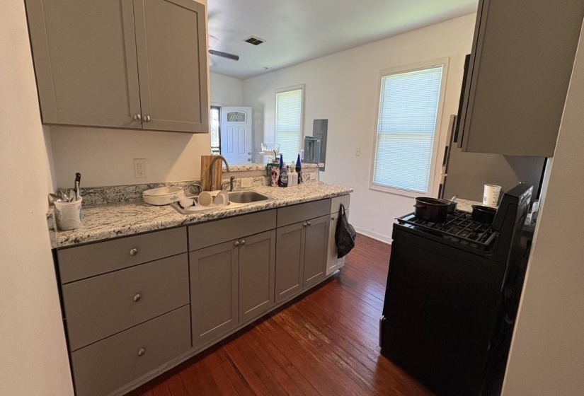 Kitchen featuring gray cabinetry with brushed nickel hardware, light-toned granite-style countertops, and a stainless steel sink with a high-arch faucet