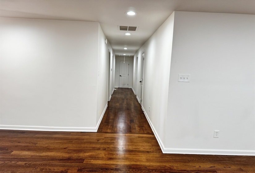 Hall with dark wood-type flooring and recessed lighting