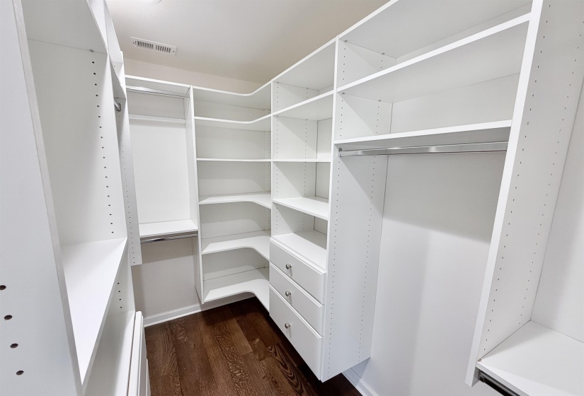 Walk in closet with dark hardwood floors, custom cabinets, and recessed lighting