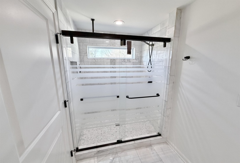 Private bathing room with marble floors, large marble walk in shower with rain feature, heated jetted jacuzzi tub, and upgraded variable lighting with blue tooth compatible speaker.